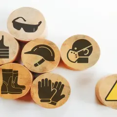 Drewniane krążki z symbolami ochrony: kamizelka, okulary, kask, maska, rękawice, buty i znak ostrzegawczy. Zapobiegają chorobie zawodowej.