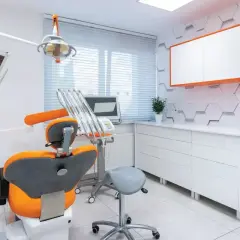 Nowoczesny gabinet stomatologiczny z fotelem dentystycznym i sprzętem.
