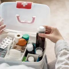 Otwarta apteczka samochodowa z lekami, plastrami i bandażami.