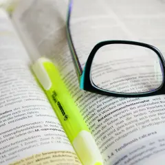 Okulary i zakreślacz na książce. Zastanawiasz się, ile trwa szkolenie BHP? To zależy od zakresu i formy, ale warto się dowiedzieć.