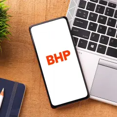 Telefon z napisem BHP obok laptopa i notatnika.