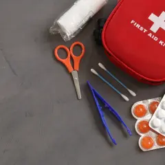 Czerwona apteczka kpp z plastrami, tabletkami, nożyczkami i pęsetą.