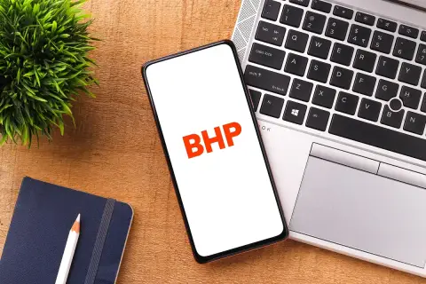 Telefon z napisem BHP obok laptopa i notatnika.