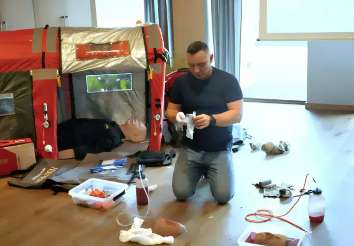 Ćwiczenie kwalifikowanej pierwszej pomocy. Instruktor przygotowuje materiały, obok manekin do nauki.