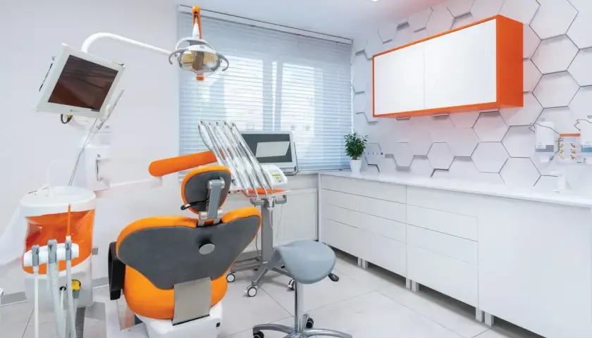 Nowoczesny gabinet stomatologiczny z fotelem dentystycznym i sprzętem.