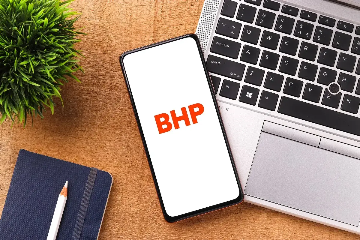 Telefon z napisem BHP obok laptopa i notatnika.